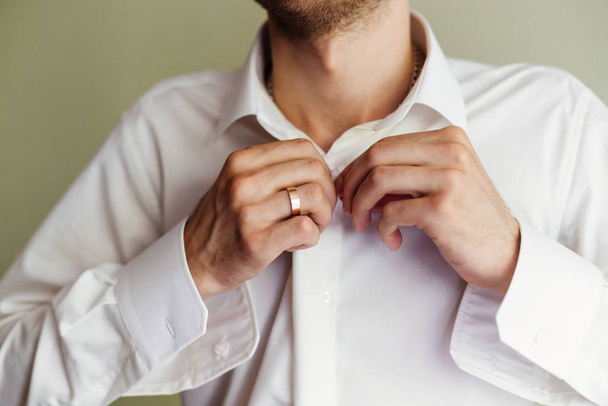 the groom in a white shirt fasten the buttons. Closeup of groom  - Zdjęcie, obraz