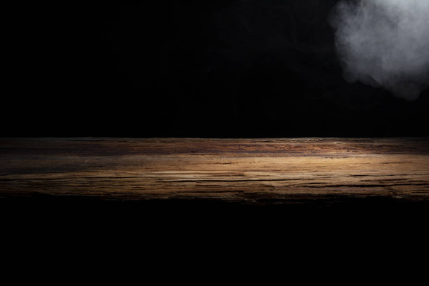 table top made of old wood with a spot of light and blue smoke in dark colors - Фото, изображение