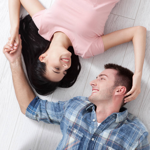 Happy young couple, lying on the floor, look at each other and dream of furniture for a new apartment. Mock up - Foto, Bild