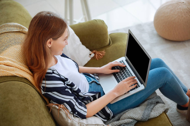Νεαρή γυναίκα με φορητό υπολογιστή ξεκουράζεται στο σπίτι - Φωτογραφία, εικόνα