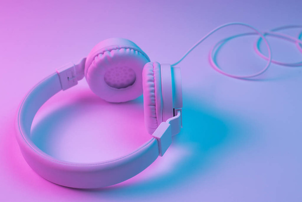 Retro 90s style photo of white stylish wireless headphone in neon lights. Music concept. - Foto, imagen