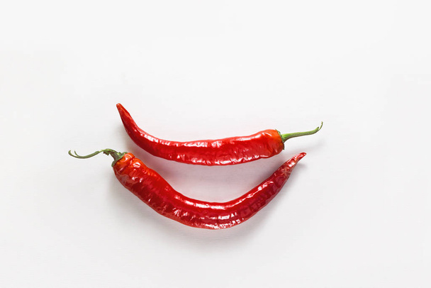 Chili pepper smile. Two whole red chili peppers on white wooden background. Flat lay, top view - Photo, Image