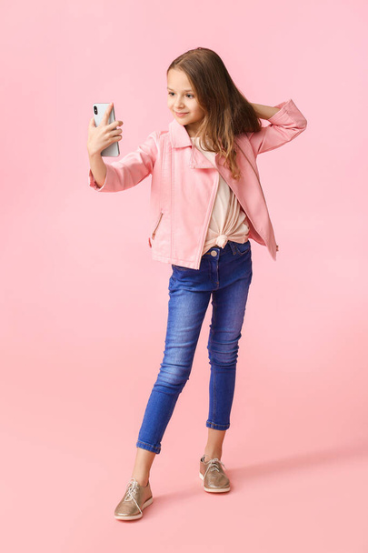 Cute little girl taking selfie on color background - Photo, Image