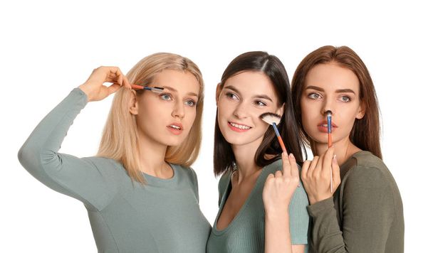 Beautiful young women applying makeup on white background - Foto, Imagen