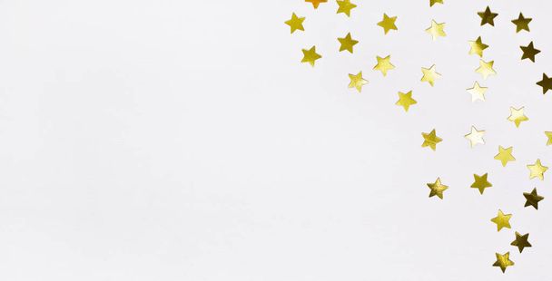 Gold star confetti on white wood background. Festive holiday golden decoration - Zdjęcie, obraz