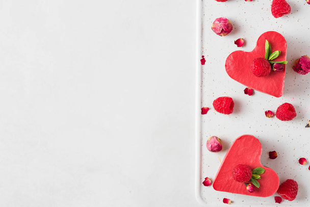 w kształcie serca czerwone surowe wegańskie ciasta ze świeżych malin, mięty i suszonych kwiatów. Deser walentynkowy. widok z góry - Zdjęcie, obraz