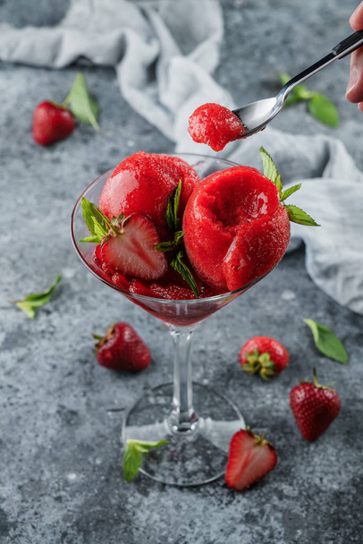 Φρέσκο κόκκινο παγωτό με φράουλες και μέντα σε ποτήρι μαρτίνι σε γαλάζιο φόντο. Καλοκαιρινό επιδόρπιο και γλυκό, κοντινό - Φωτογραφία, εικόνα