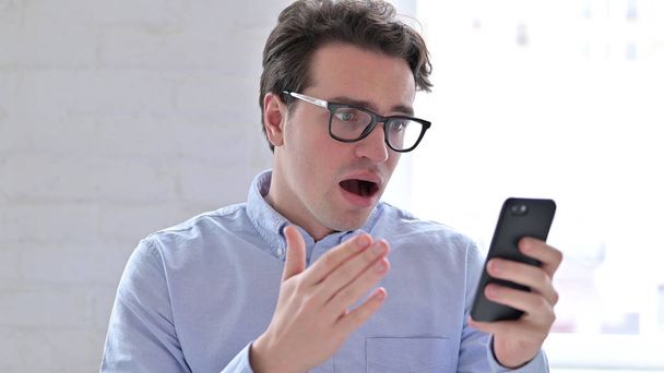 Portrait de jeune homme réagissant à l'échec sur Smartphone
 - Photo, image