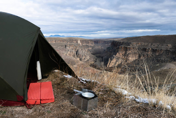 Camping spot con tenda verde, materasso rosso e piano cottura in Valle Ihlara in Turchia. Inverno nel deserto
. - Foto, immagini
