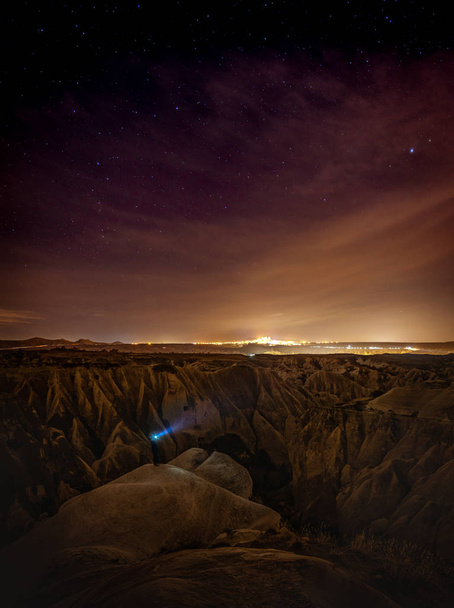 Panoramic view of red valley in Cappadocia at night with stars in the background and person in the middle surounded by rock formations. Astrophotography in Turkey. Background blank space image. - Photo, Image