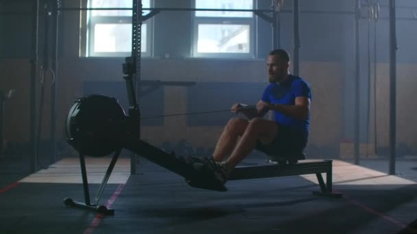 Lassú mozgás: fitness férfi sportoló edzés evezős gép testmozgás intenzív kitartás edzés kihívás erős sportoló fizikai gyakorlat tornaterem egészséges életmód motiváció - Felvétel, videó