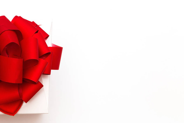 Gift or gift box with a beautiful red bow on a white background top view. Greeting card for Valentine's Day - Fotó, kép