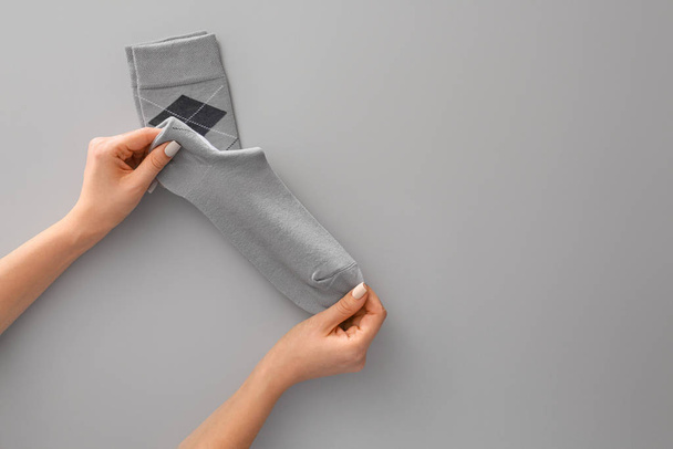 Frauenhände und Socken auf grauem Hintergrund - Foto, Bild