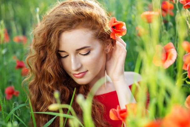 Beautiful young woman in poppy field. Beautiful make-up. The concept of health, nature, cosmetics - Фото, изображение