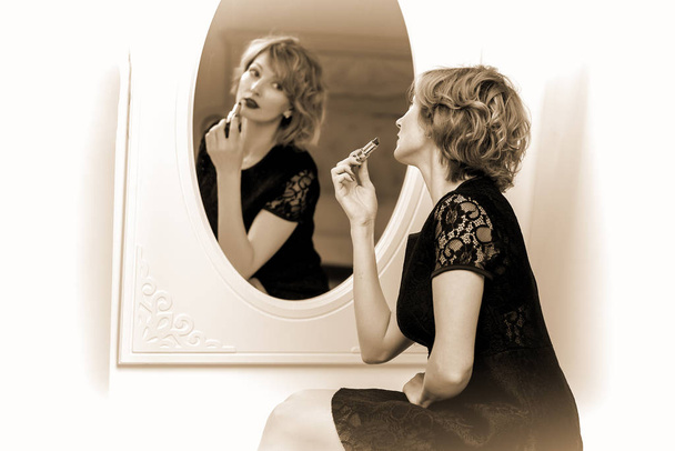 Young woman uses mascara near the mirror. Beauty and care. Studi - Zdjęcie, obraz