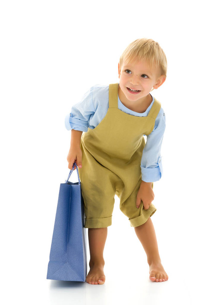 Little boy waving multicolored paper bags. He goes shopping - Foto, afbeelding