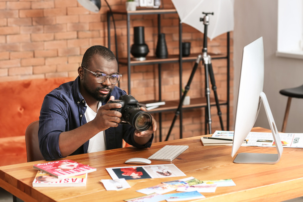 Fotógrafo afroamericano en mesa en estudio
 - Foto, Imagen