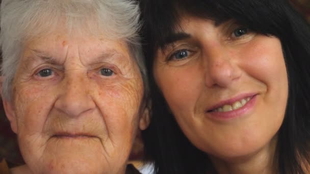 Portrait of elderly woman with her adult daughter looking into camera and showing joyful emotions. Happy women smiling enjoying warm family relationships. Slow motion Close up - Video, Çekim