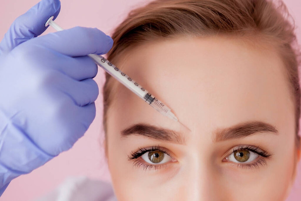 The doctor cosmetologist makes the Rejuvenating facial injections procedure for tightening and smoothing wrinkles on the face skin of a beautiful, young woman in a beauty salon.Cosmetology skin care - Φωτογραφία, εικόνα