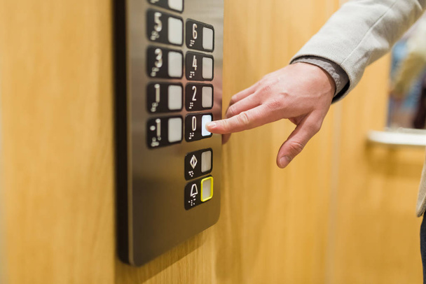 Close up of businessman pressing button in modern elevator. - Photo, image