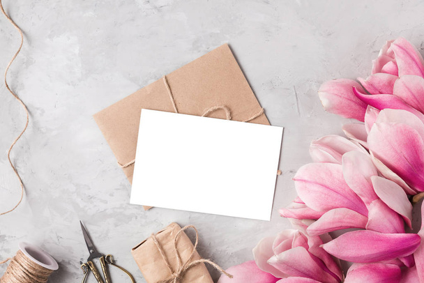 Layout creativo realizzato con fiori di magnolia rosa, biglietto di auguri, confezione regalo e corda su sfondo grigio. Piatto. Scherzi?
 - Foto, immagini
