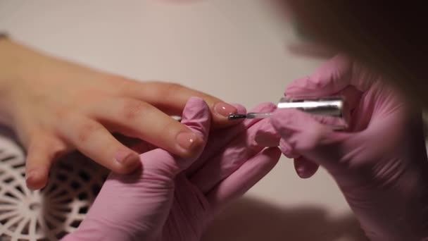 Κοντινό πλάνο των γυναικών ζωγραφίζει τα νύχια. Μανικιούρ τέχνη νυχιών. Η γυναίκα δουλεύει με ροζ γάντια. Κοντινό πλάνο των χεριών των γυναικών - Πλάνα, βίντεο