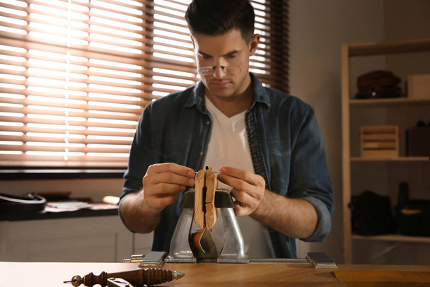 Man sewing piece of leather in workshop - Zdjęcie, obraz