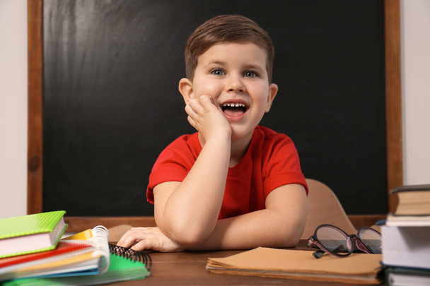 Cute little child at desk in classroom. First time at school - Foto, Imagem