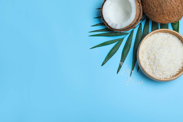 Flat lay composition with fresh coconut flakes on light blue background. Space for text - Foto, afbeelding