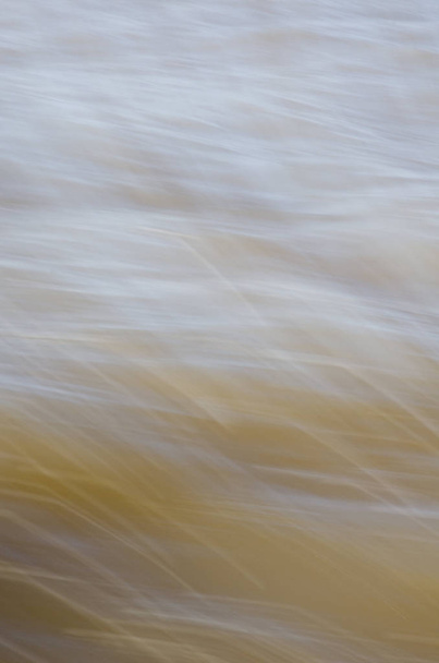 Gyors mozgású víz textúrája sárgás lágy tónusokban. - Fotó, kép