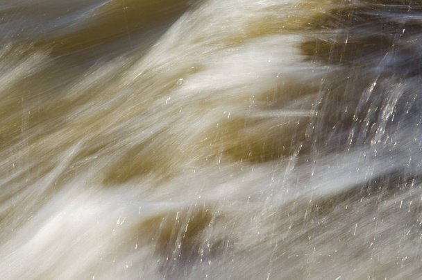 A gyorsan mozgó víz szerkezete sárgás tónusokban. - Fotó, kép