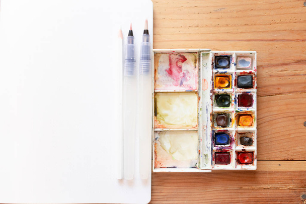 Watercolor paint canva and brushes used to create new paintings. Starting a bullet journal in a dot notebook. New beginnings. Art and creativity concept. - Zdjęcie, obraz