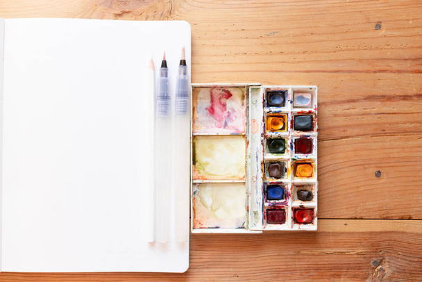 Watercolor paint canva and brushes used to create new paintings. Starting a bullet journal in a dot notebook. New beginnings. Art and creativity concept. - Foto, Bild