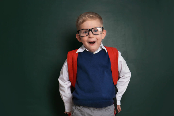 Funny little child wearing glasses near chalkboard. First time a - Фото, изображение