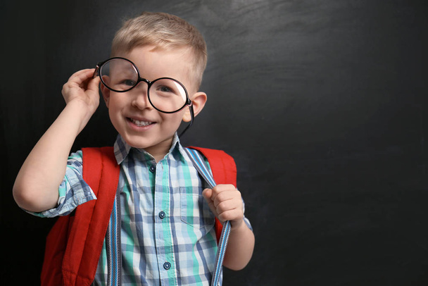 Funny little child wearing glasses near chalkboard, space for te - Foto, Imagen