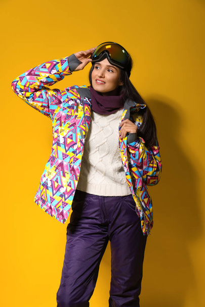 Woman wearing stylish winter sport clothes on yellow background - Foto, afbeelding