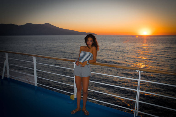 Asiática adolescente en tubo superior de pie en la cubierta de ferry mirando hacia otro lado fr
 - Foto, Imagen