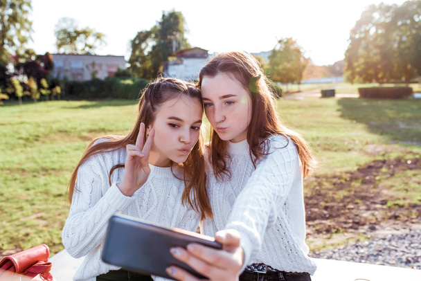 Two girls schoolgirl girlfriends 12-14 years old, taking pictures of themselves on phone, selfie portrait, recording video on social networks, air kiss, online communication in Internet application. - Φωτογραφία, εικόνα