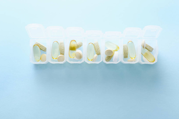 Boîte à pilules quotidienne ouverte sur fond bleu
. - Photo, image