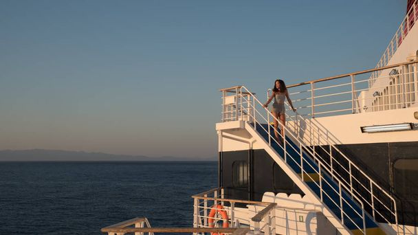 Teen girl in shorts standing on top of blue stairway on ferry bo - Foto, Imagem