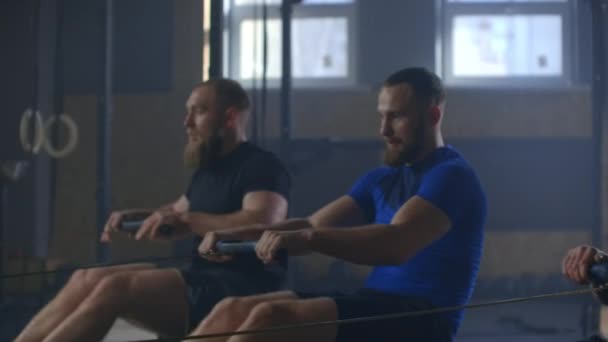 Entrenamiento de amigos de fitness en la máquina de ergómetro fila en el gimnasio cruzado
 - Metraje, vídeo