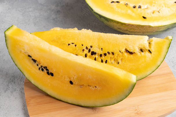 Sliced yellow watermelon on a wooden cutting board on a table - Photo, Image