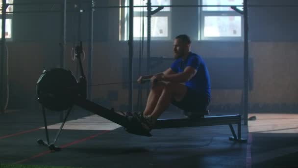 Lassú mozgás: fitness férfi sportoló edzés evezős gép testmozgás intenzív kitartás edzés kihívás erős sportoló fizikai gyakorlat tornaterem egészséges életmód motiváció - Felvétel, videó