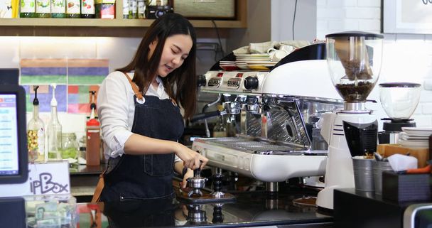 Ασιάτισσες Barista χαμογελώντας και χρησιμοποιώντας μηχανή καφέ στον πάγκο της καφετέριας - Working woman small business owner food and drink cafe - Φωτογραφία, εικόνα