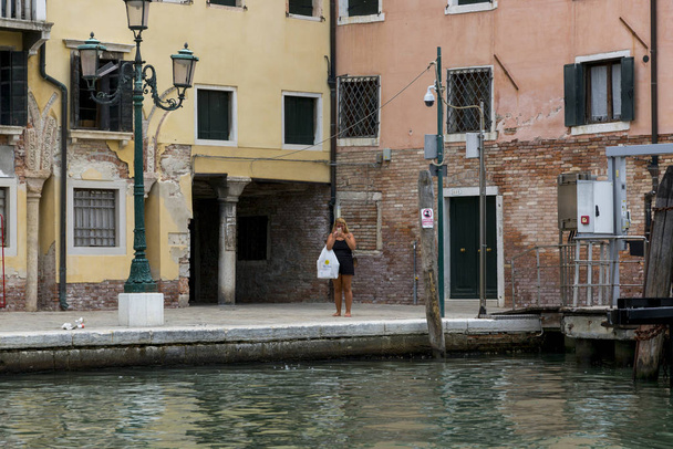 Wenecja, Włochy - 22 sierpnia 2019: Dziewczyna na promenadzie w Wenecji robi selfie - Zdjęcie, obraz