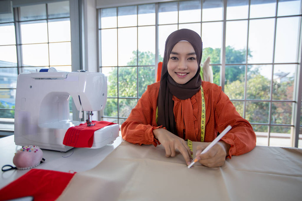 Малый бизнес мусульманских женщин модельер Работа и использование смартфона и планшета с платьями в магазине одежды
 - Фото, изображение