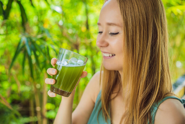 Young woman drinks Celery Juice, Healthy Drink, bunch of celery on a wooden background - Fotoğraf, Görsel