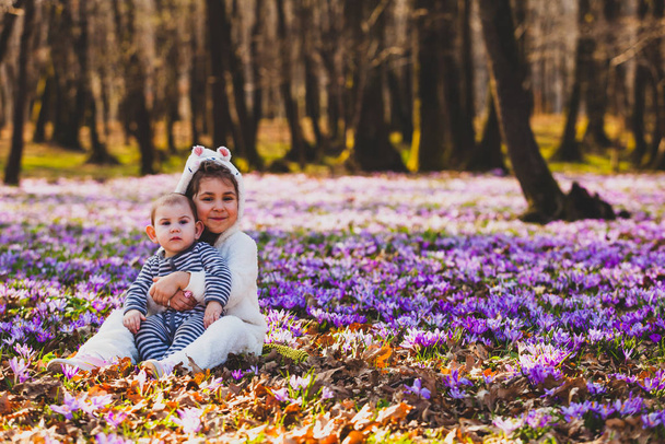 Sister and brother sitting in the middle of crocus valley - Фото, изображение