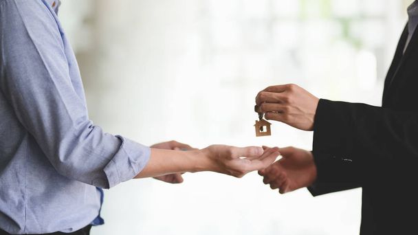 Close up view of real estate agent giving house key to his customer after finished signing home loan agreement - Photo, Image