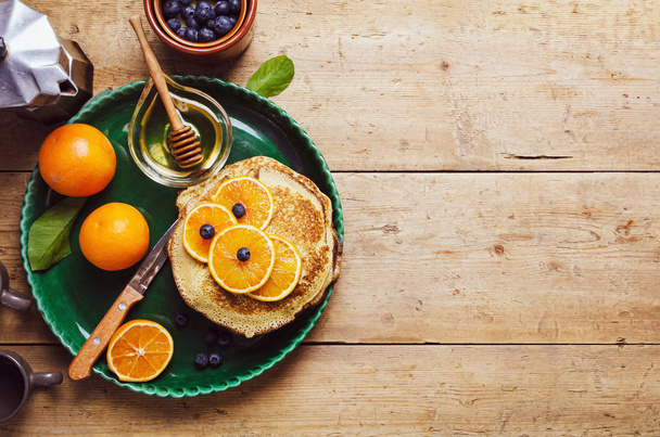 Stack of pancakes with orange and blueberries and honey syrup. - Fotó, kép
